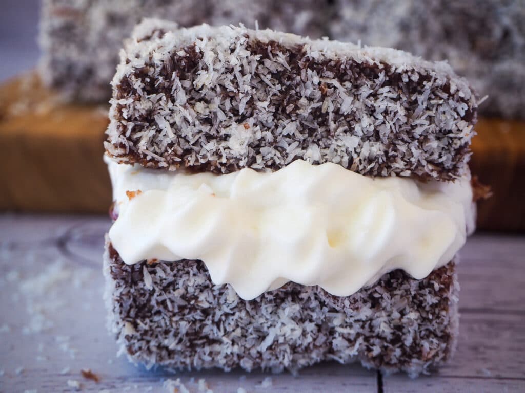 Close up lamington filled with jam and cream.
