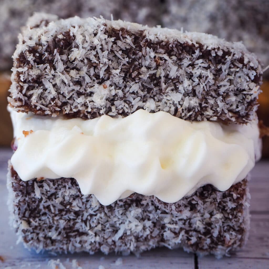 Close up lamington filled with jam and cream.