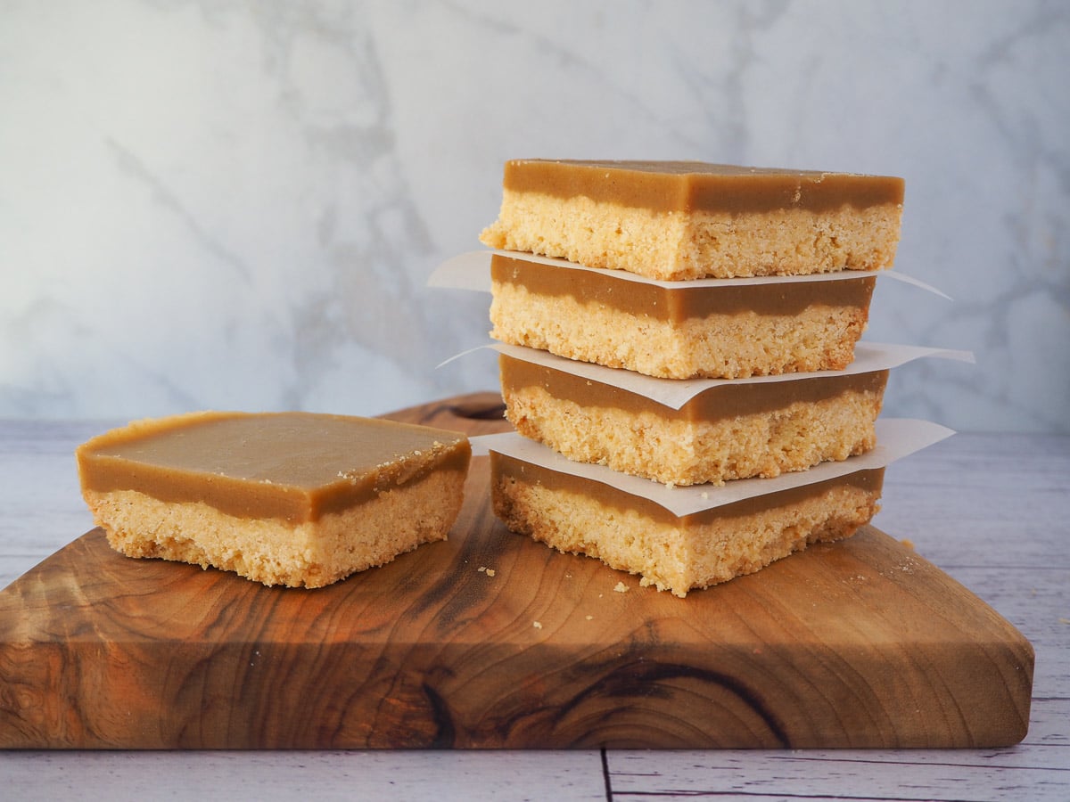 Stack of ginger crunch with a piece of ginger crunch to the side, on a board.