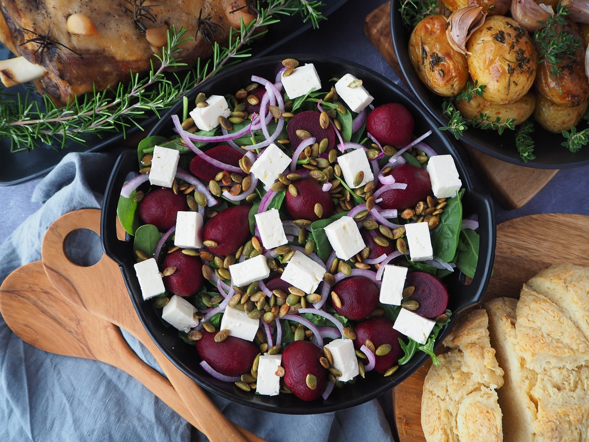 Beetroot salad on a plate, with damper and roasted mini potatoes on the side.