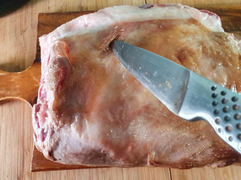 Cutting slits into the browned lamb.