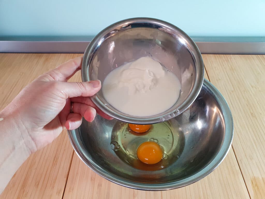 Adding milk and yogurt to eggs.