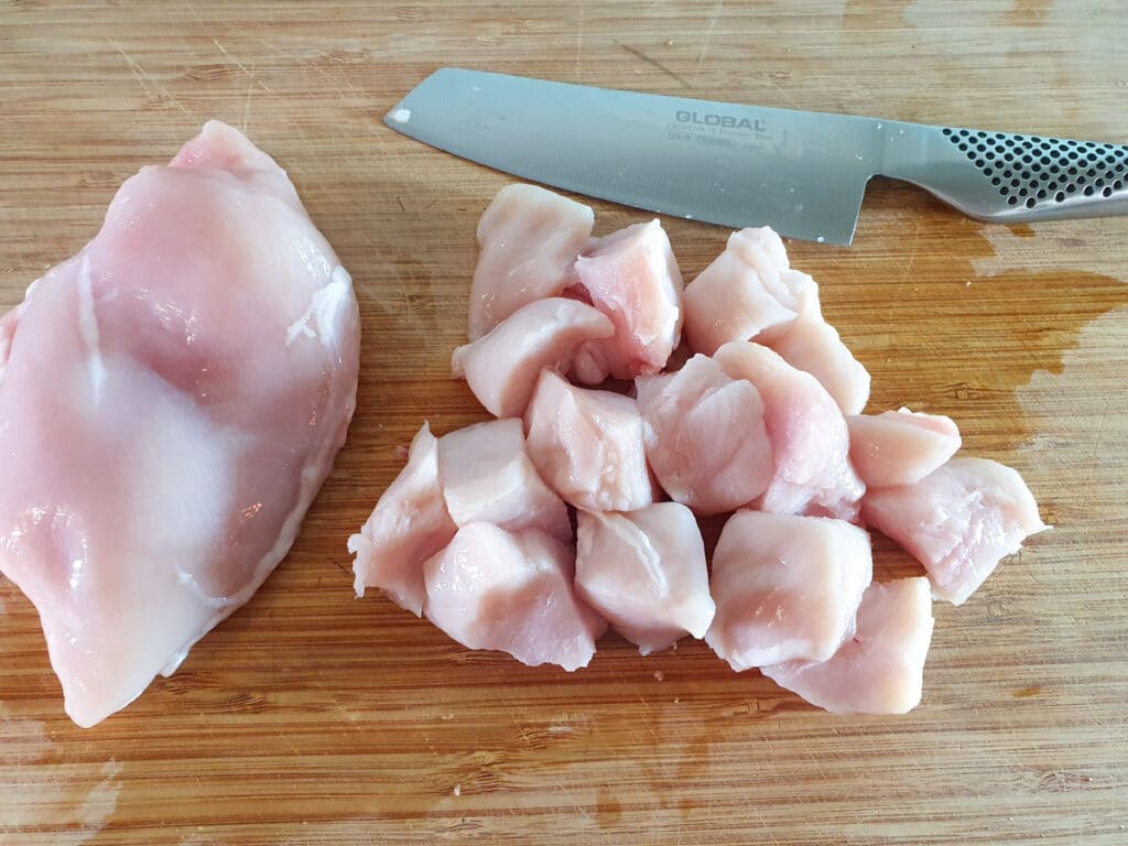 Chopping chicken into cubes.
