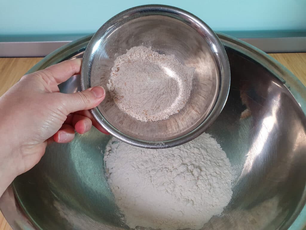 Adding wholemeal flour to plain flour.