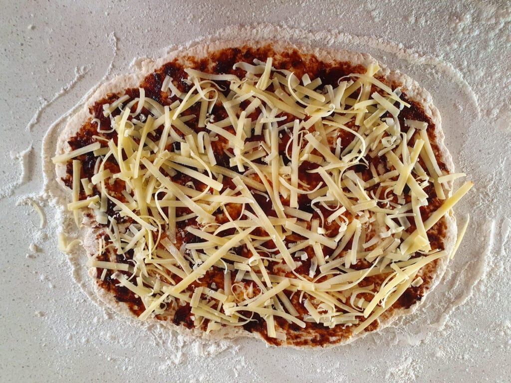 Dough with cheese sprinkled over the vegemite.