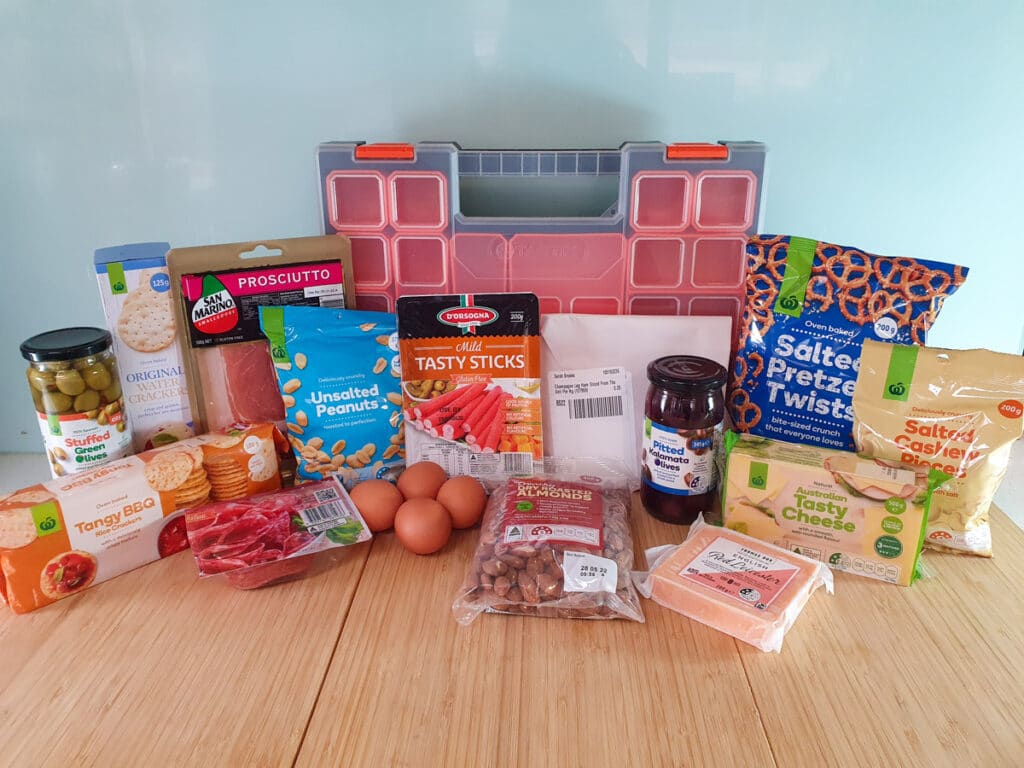 Ingredients: green stuffed olives, BBQ rice crackers, plain water crackers, prosciutto, salami, peanuts, eggs, twiggy sticks, roasted almonds, ham, pitted Kalamata olives, red Leicester cheese, tasty cheese, salted pretzels, salted cashews, multi compartment tool box.