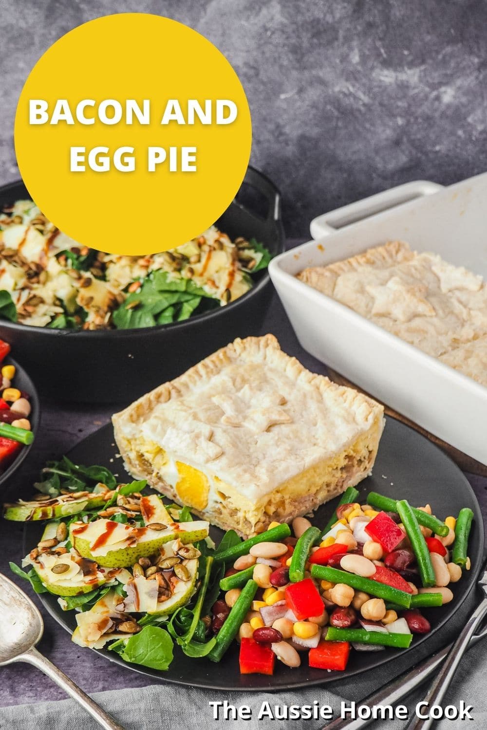 Pie in a plate with salads, with pie dish and salads in background, and text overlay Bacon and Egg Pie and The Aussie Home Cook.