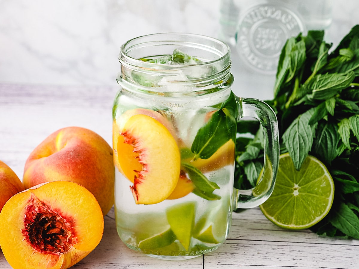 Peach infused water with lime and mint, with fresh peaches, lime and mint on the side.