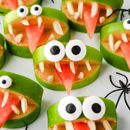 Close up apple monsters on a plate with toy spiders.