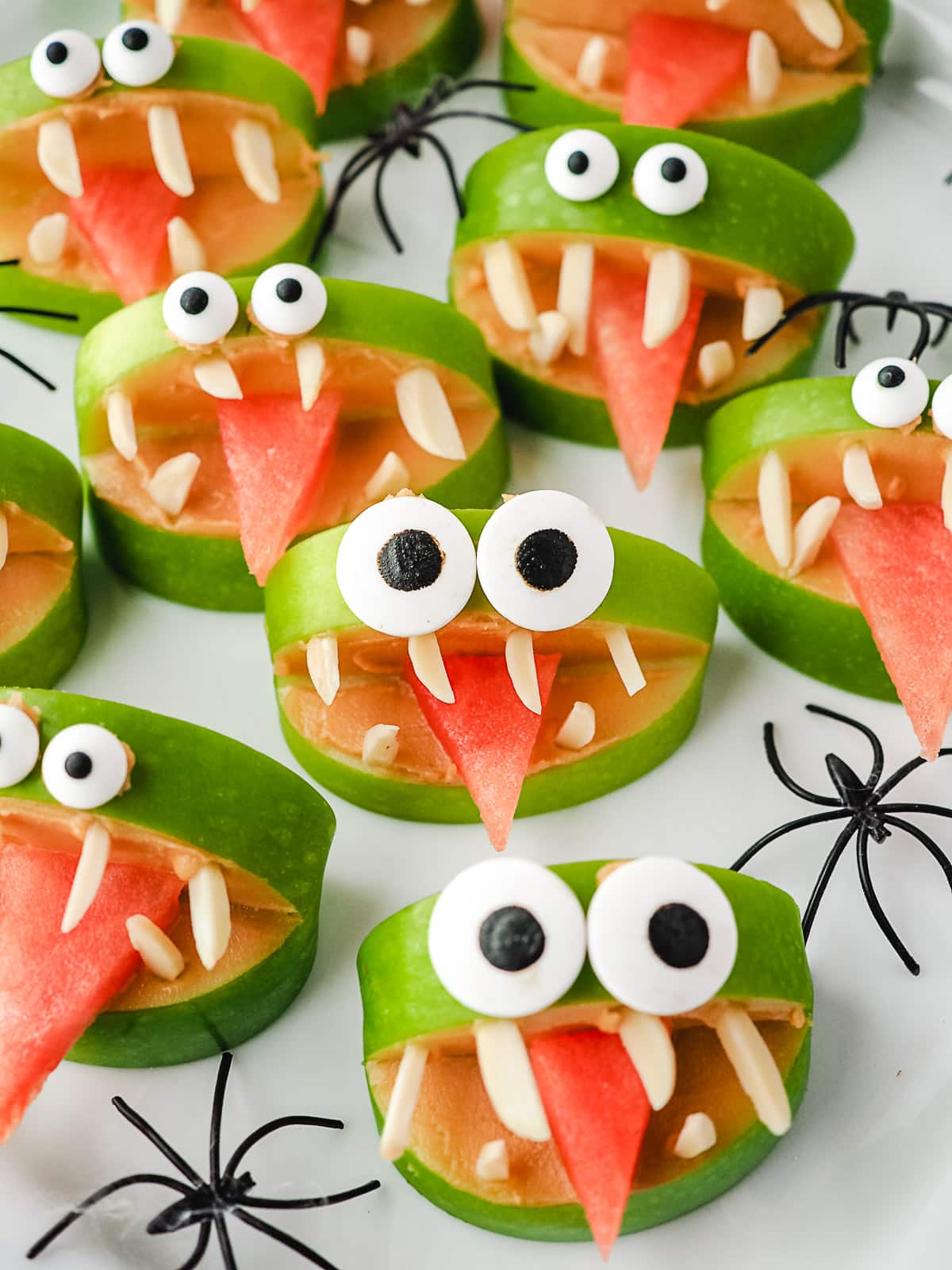Apple monsters on a plate with toy spiders.