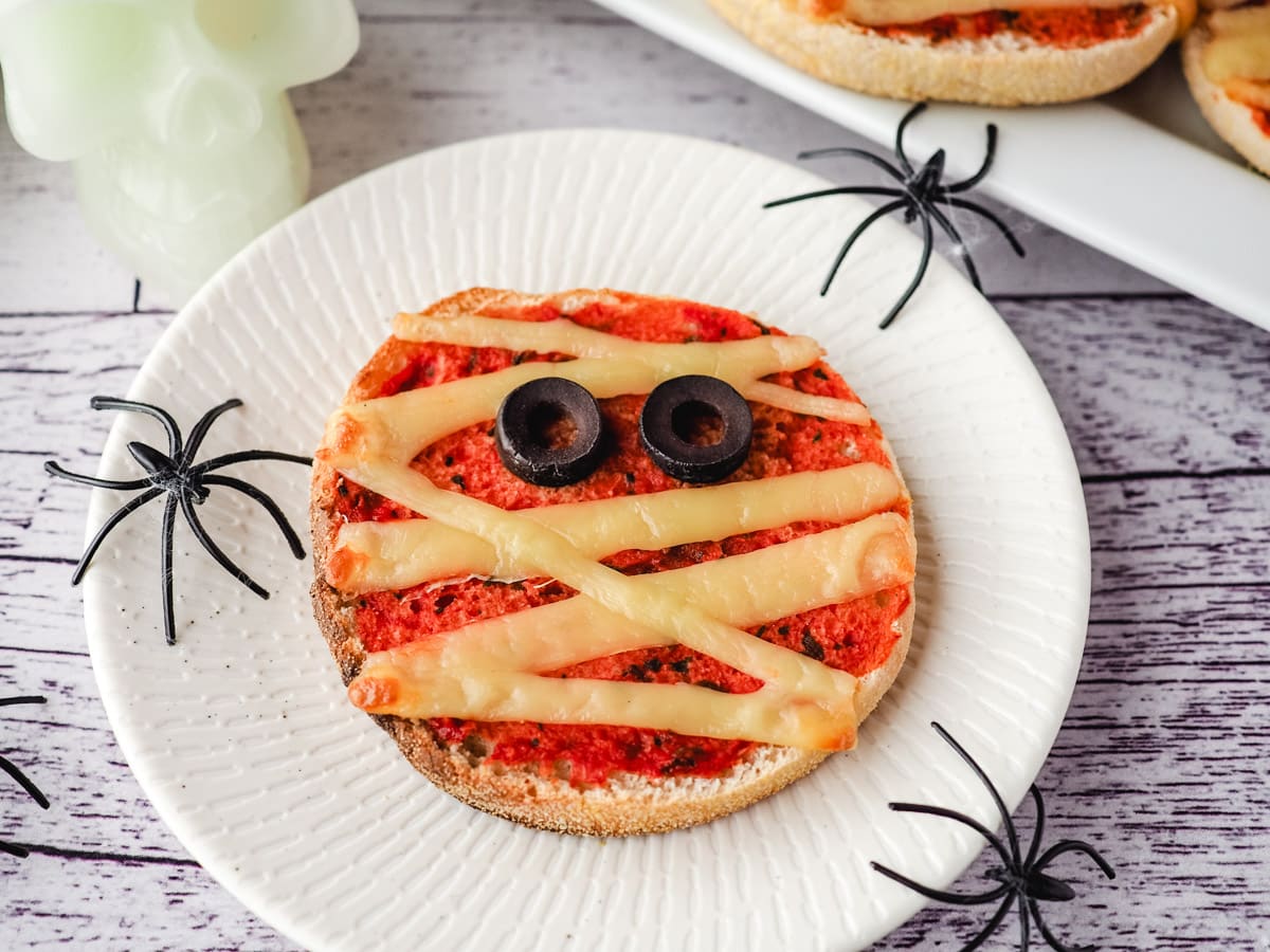 Pizza on a plate with Halloween spider decorations.