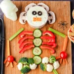 Close up veggie tray on a board with Halloween skuls and spiders.