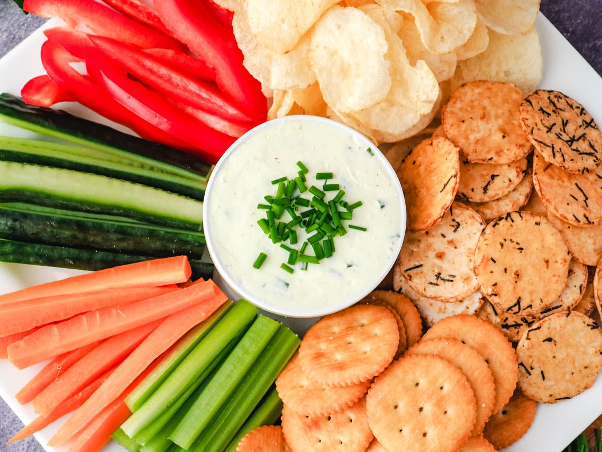 Sour cream dip with chips, rice crackers, ritz crackers and veggie sticks, celery, carrots, cucumber and red pepper.